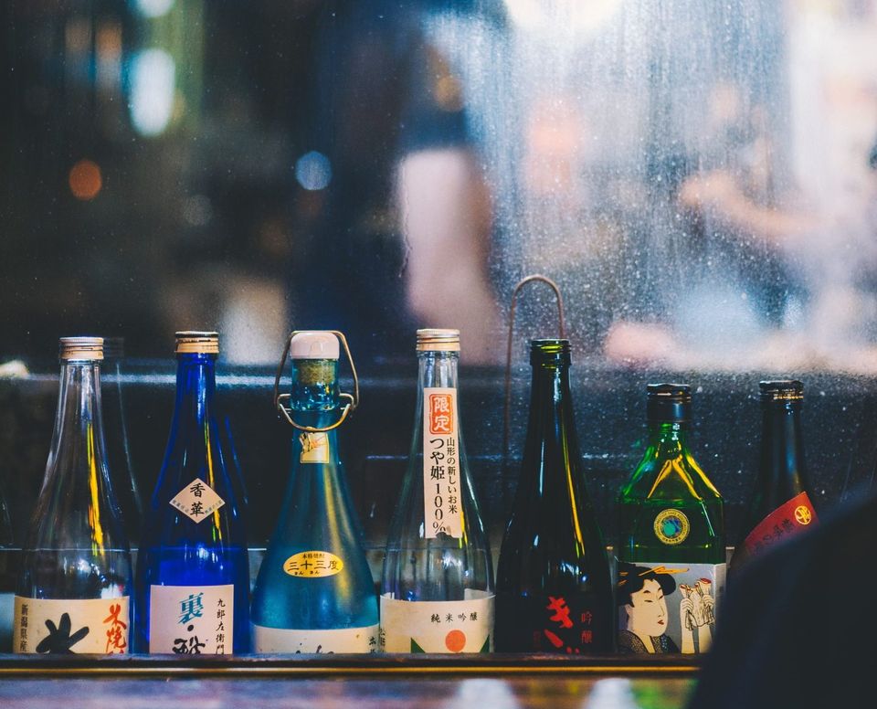 Sakeflaschen aufgereiht auf einer Bartheke in Tokio