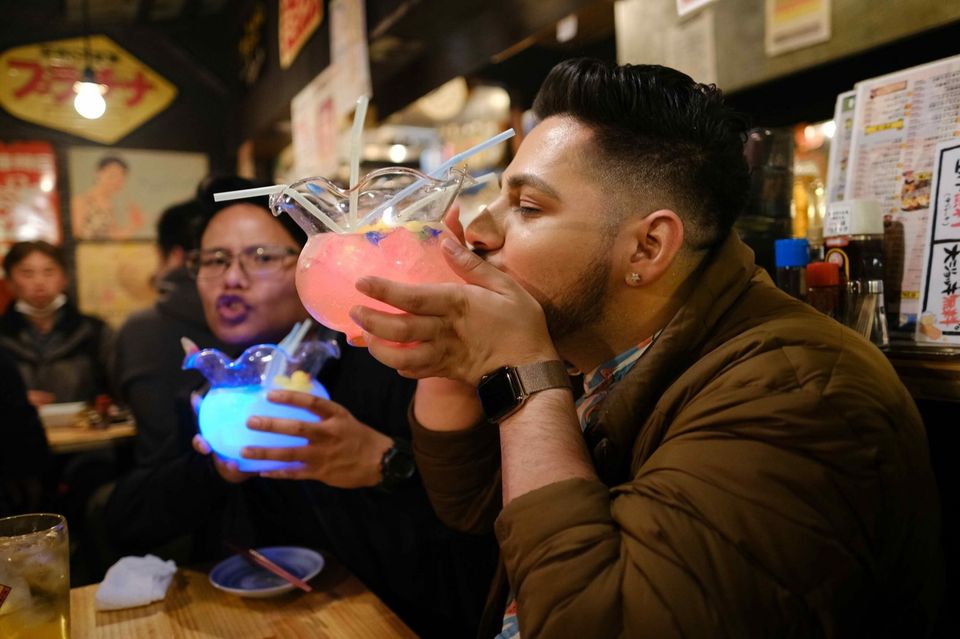 Zwei Freunde stoßen mit Getränken in einer Bar in Tokio an