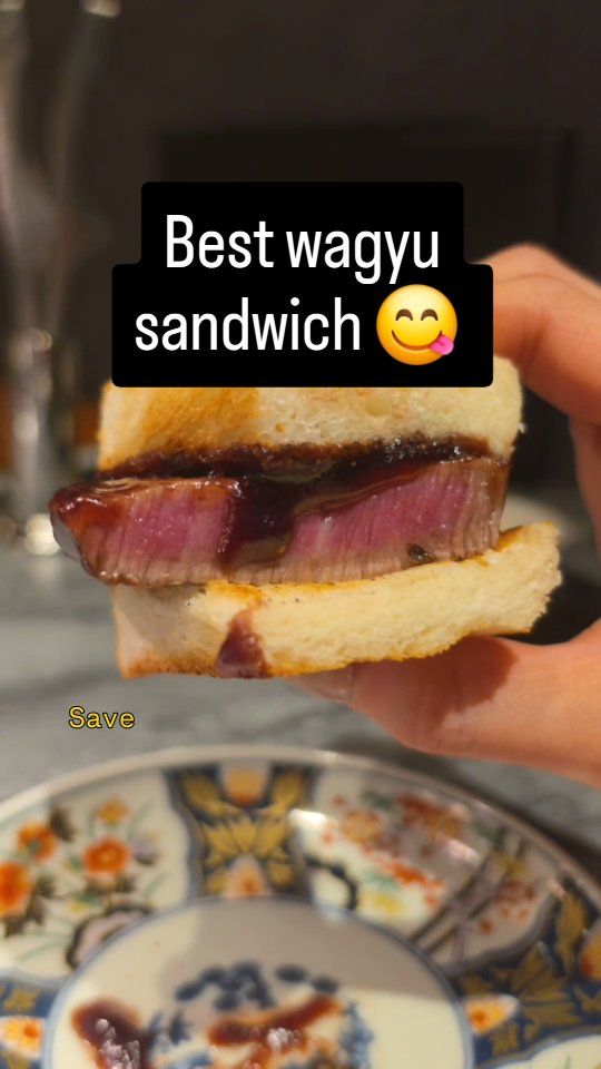 Hand hält ein dickes Wagyu-Sandwich