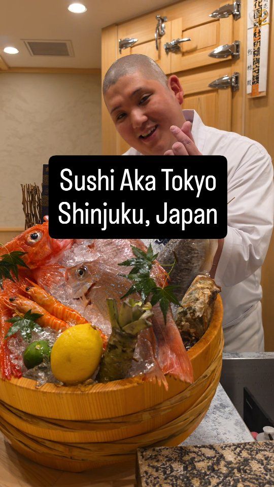 Lächelnder Sushi-Chef im Sushi Aka in Shinjuku mit einem Bottich frischer Meeresfrüchte