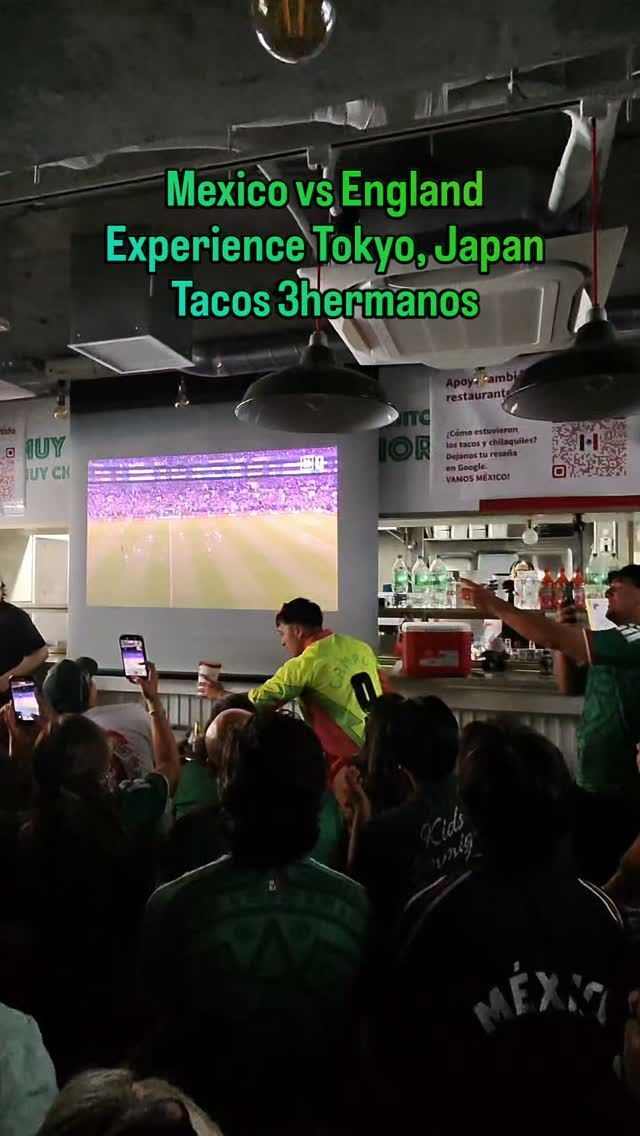 Fans in grünen Trikots verfolgen ein WM-Spiel Mexikos auf einer Großleinwand in einem Taco-Restaurant in Tokio
