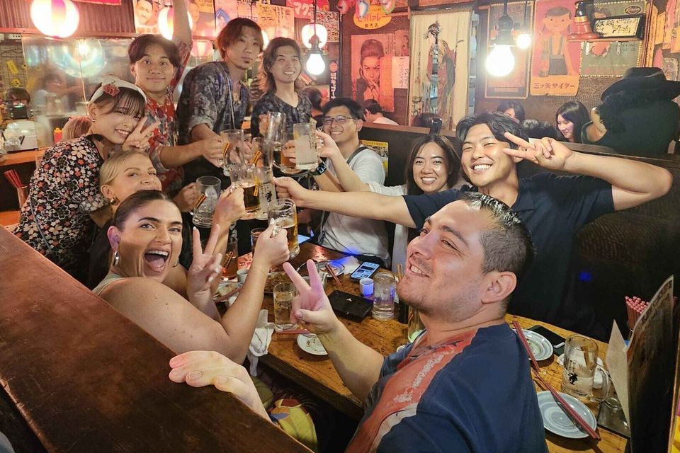 Large group toasting drinks inside a vintage Tokyo izakaya