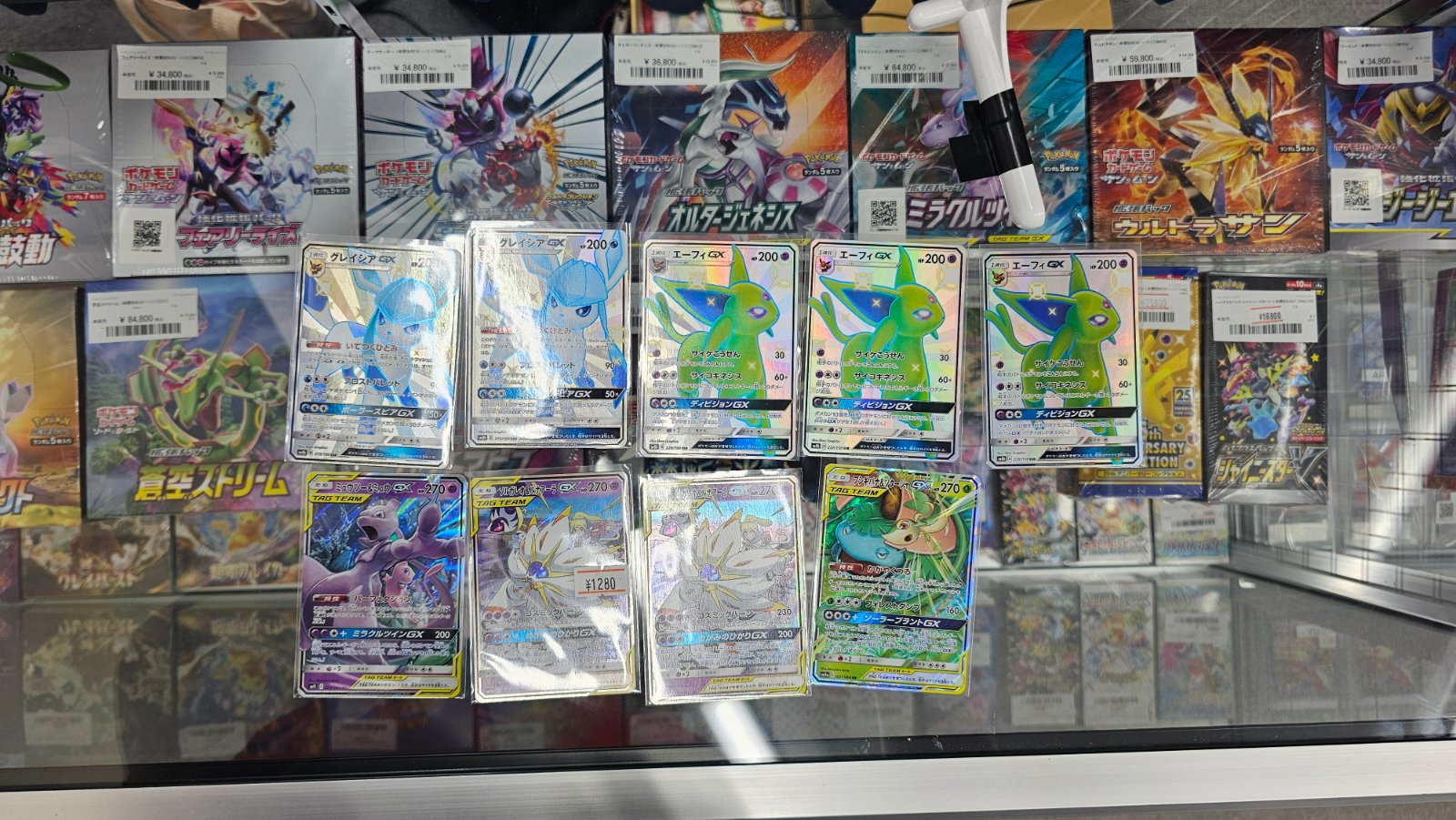 Japanese Pokémon cards displayed in a glass case with sealed card boxes behind them