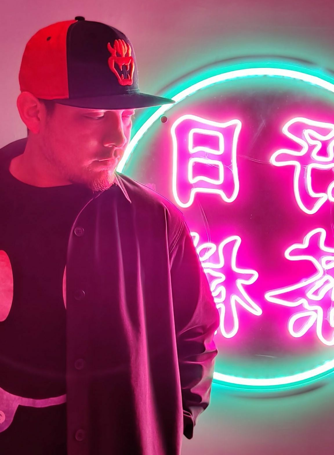 Man posing before a glowing neon sign in Tokyo