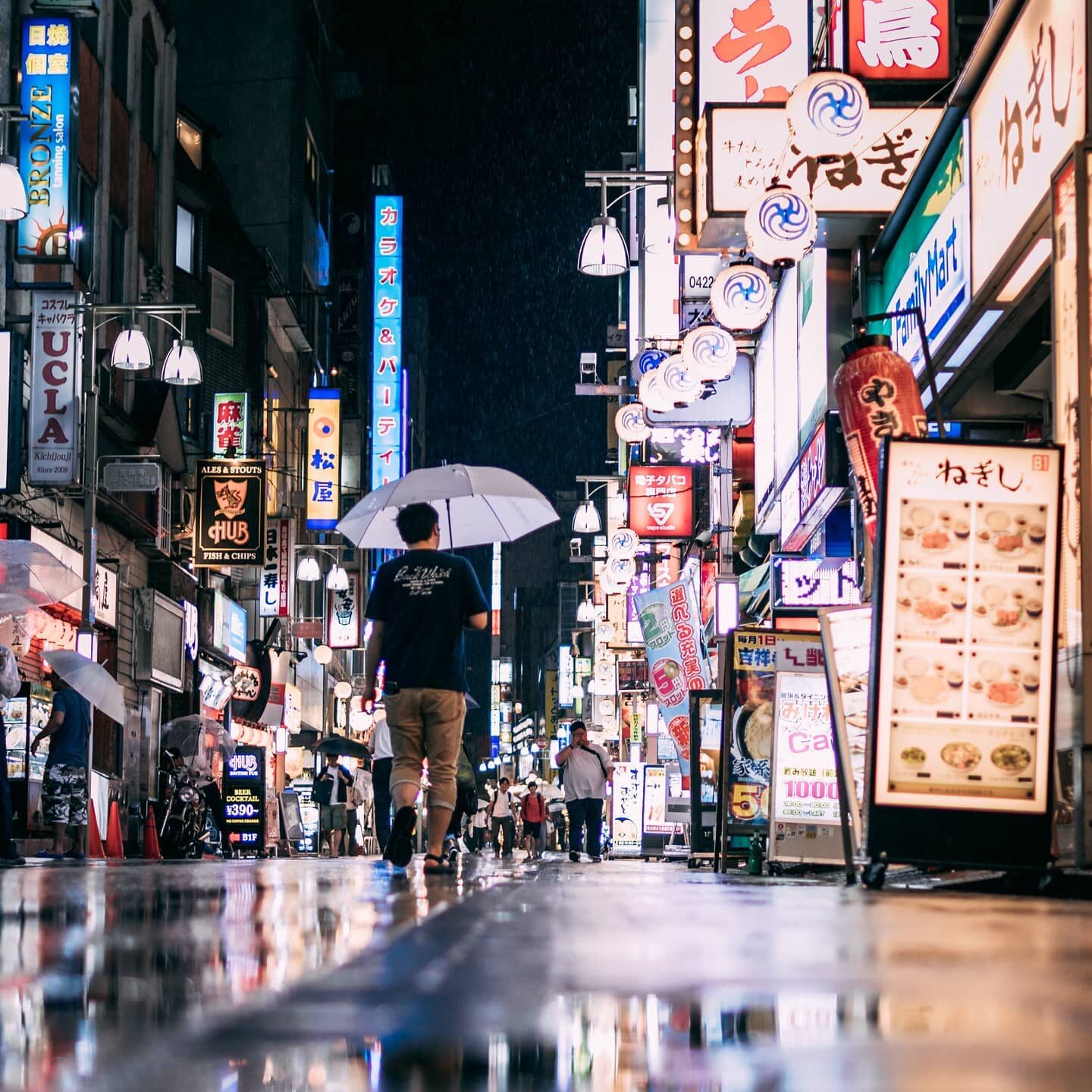 Rainy night street glowing with Tokyo neon signs