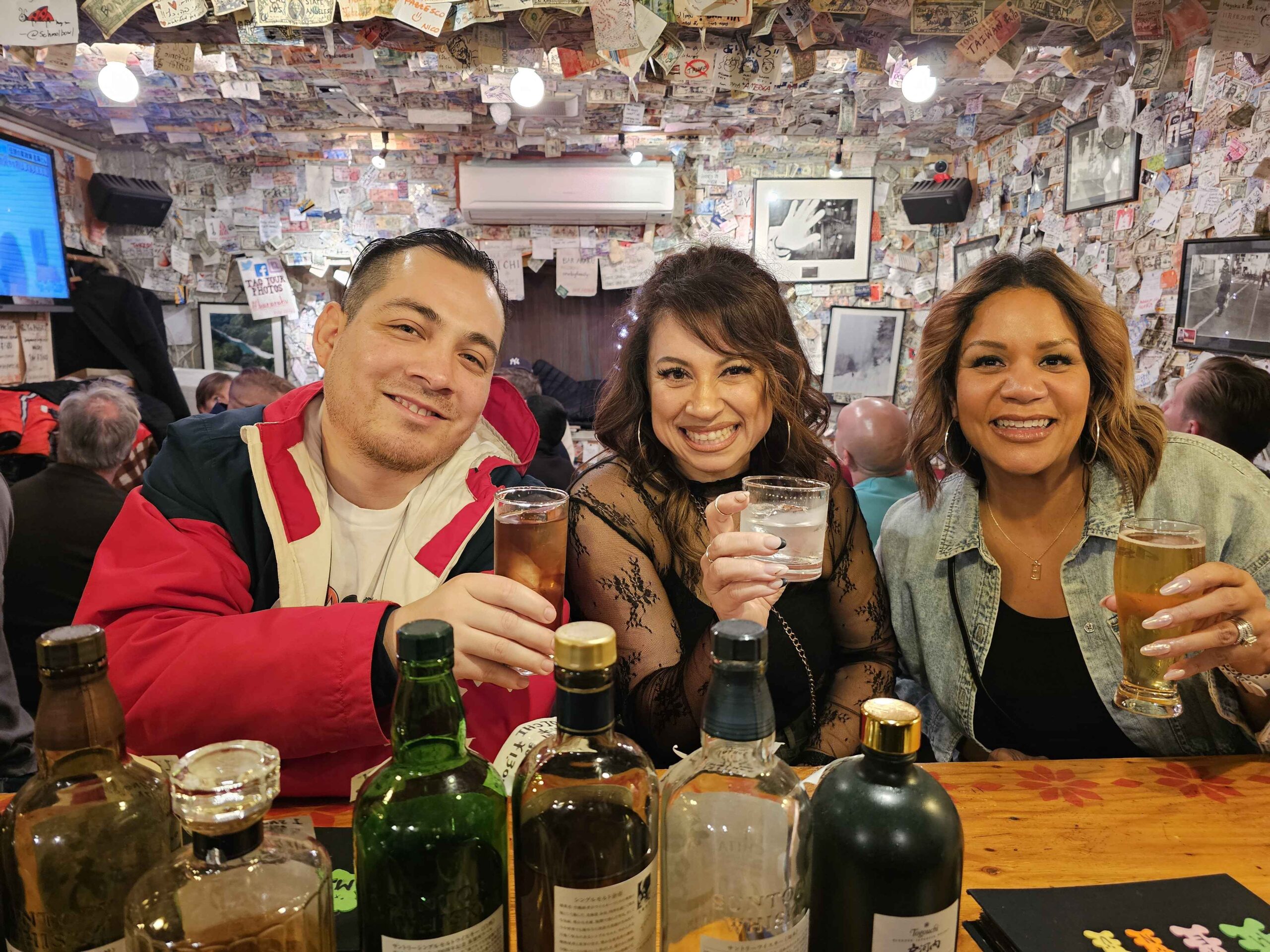Friends with drinks inside a Tokyo bar with money-covered walls