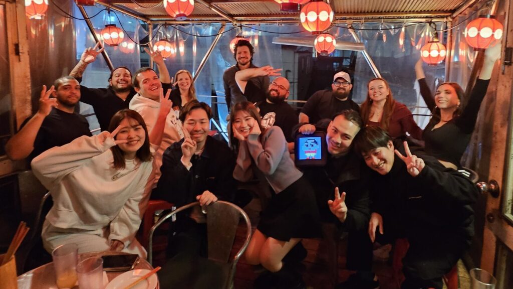 Group photo under red lanterns at a Tokyo izakaya