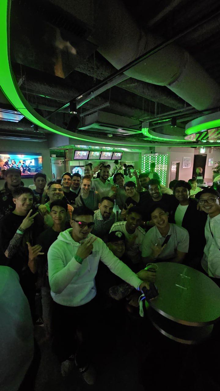 Tour group posing inside a neon-lit Tokyo bar